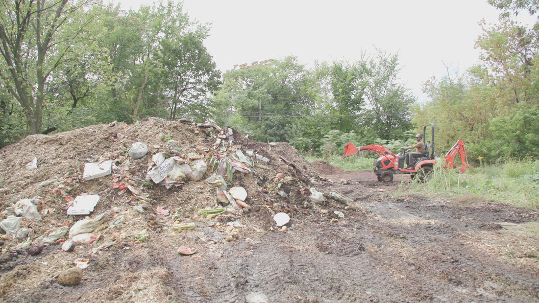 A tractor moving food waste in a compost pile