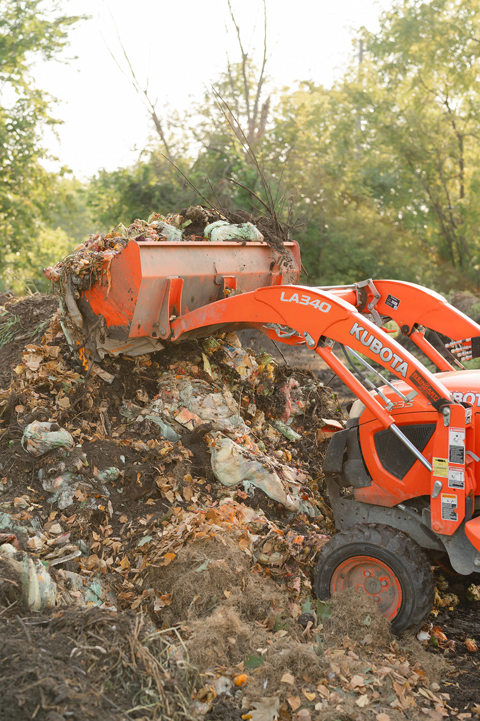 An orange tractor moving food waste to turn into compost